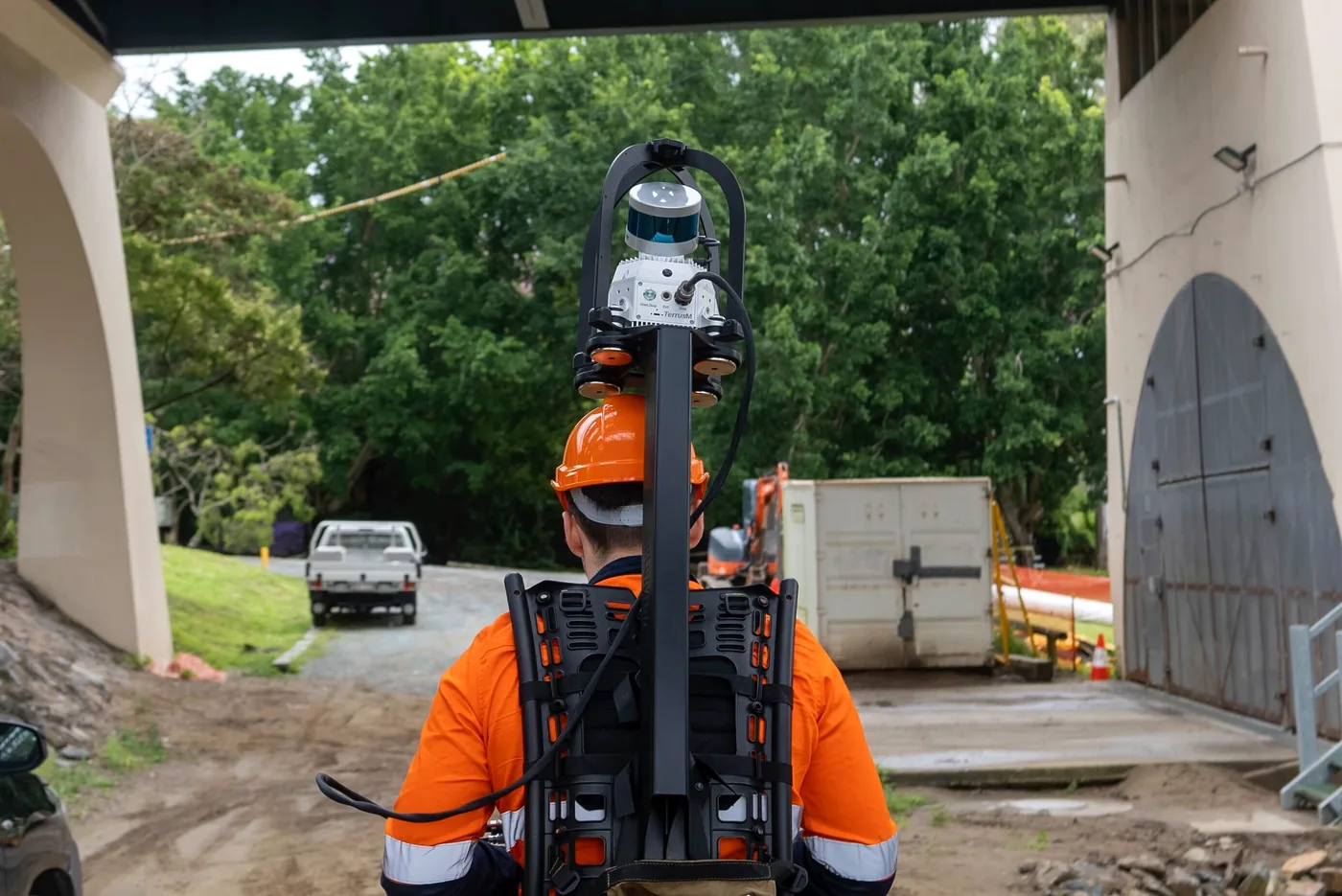 Surveyor wearing the TerrusM backpack walking toward the underside of the Walter Taylor Bridge